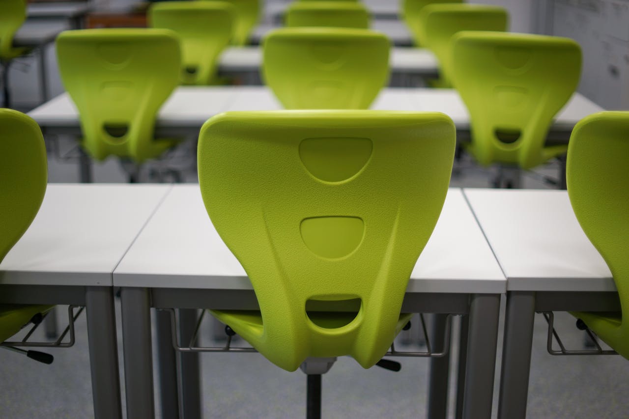 Rows of bright green chairs at white desks in a modern classroom setting.